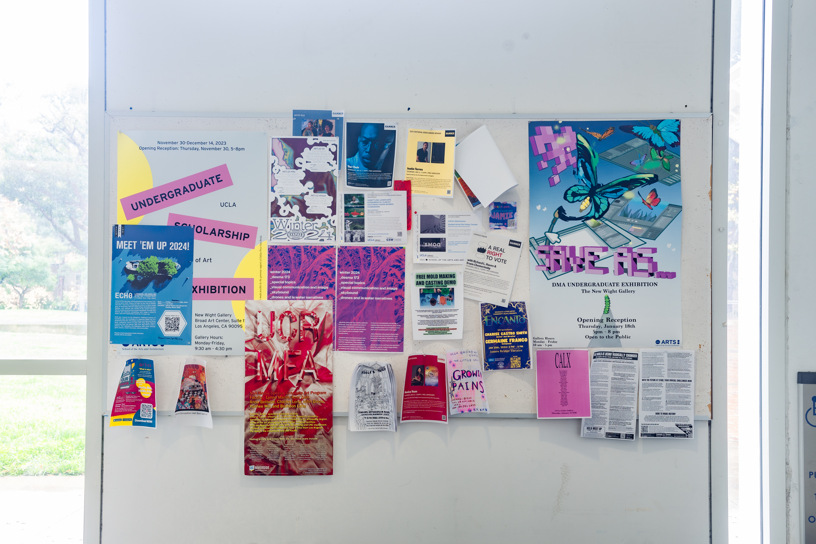 A busy corkboard on a white wall with multiple posters and advertisements.